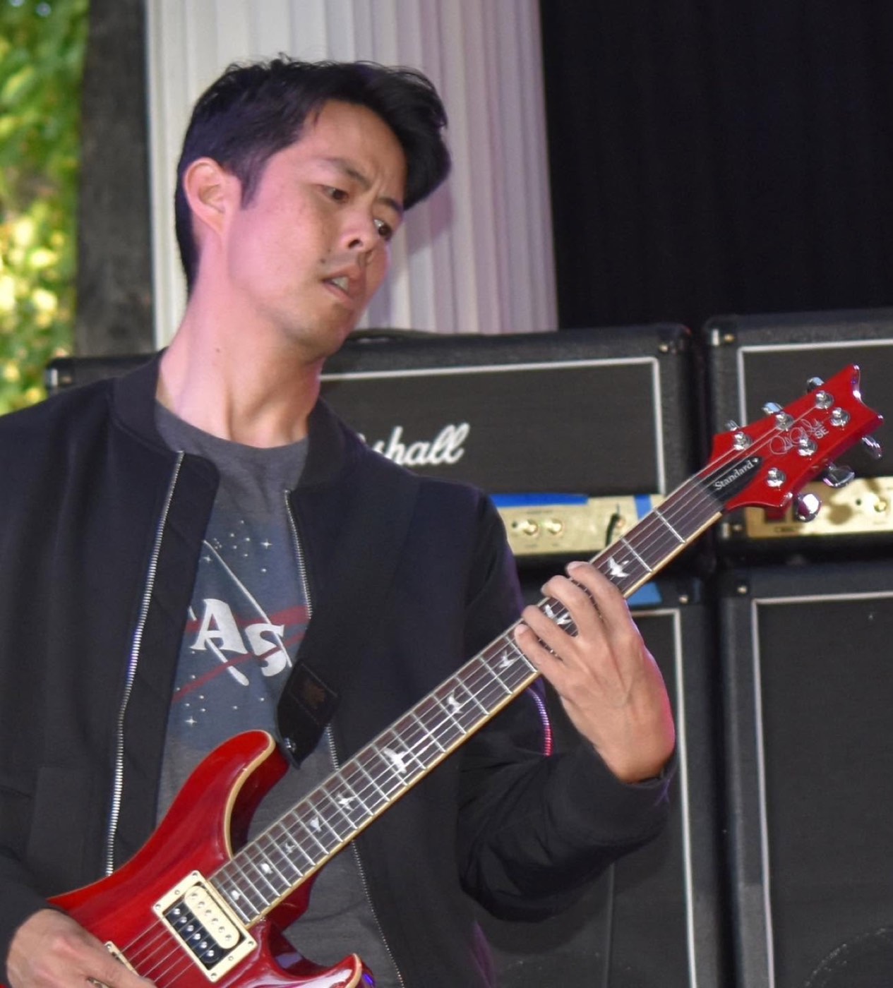 Aaron playing a red electric guitar outdoors